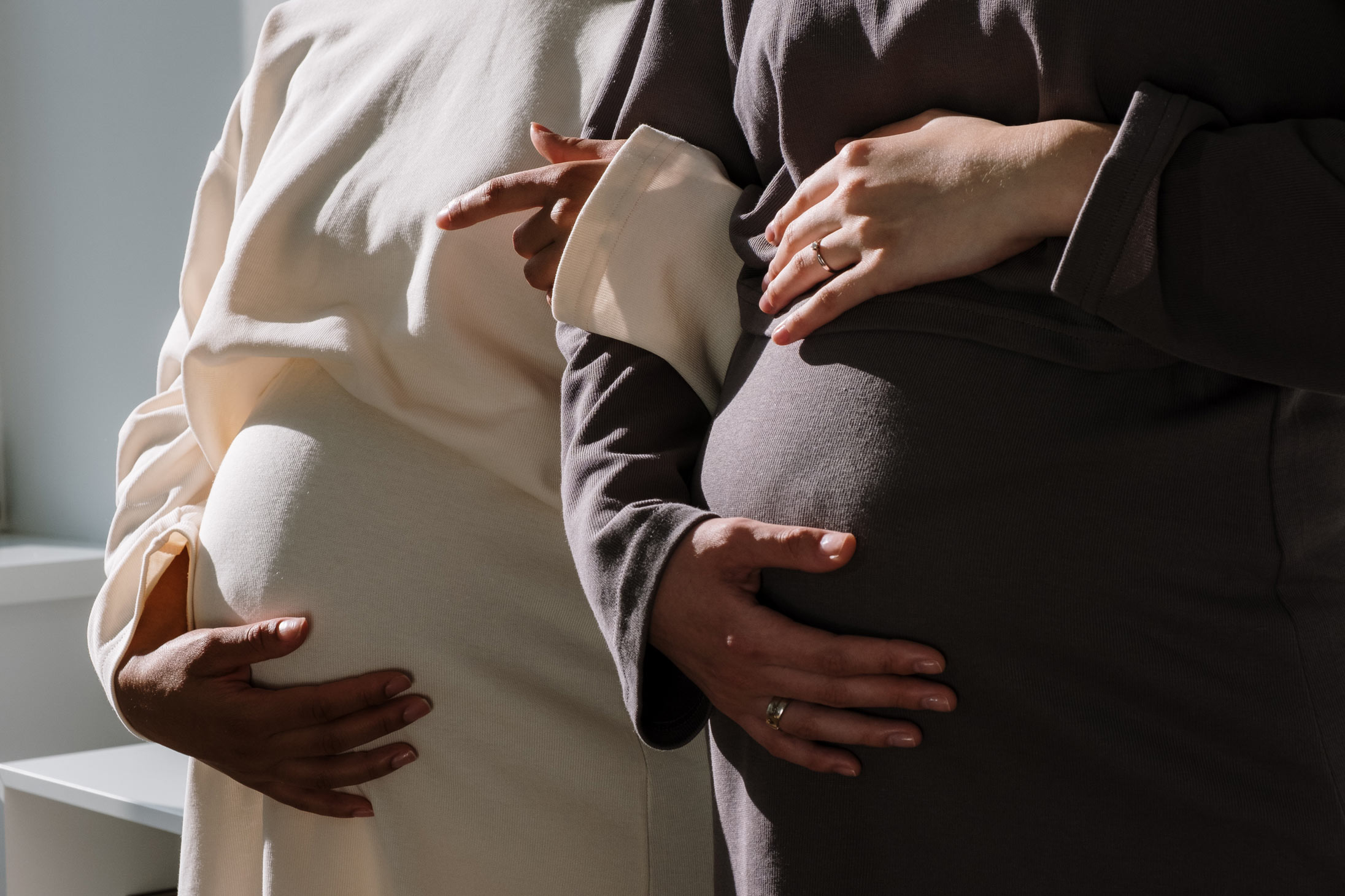 Two pregnant women holding their bellies in celebration of Mother's Day